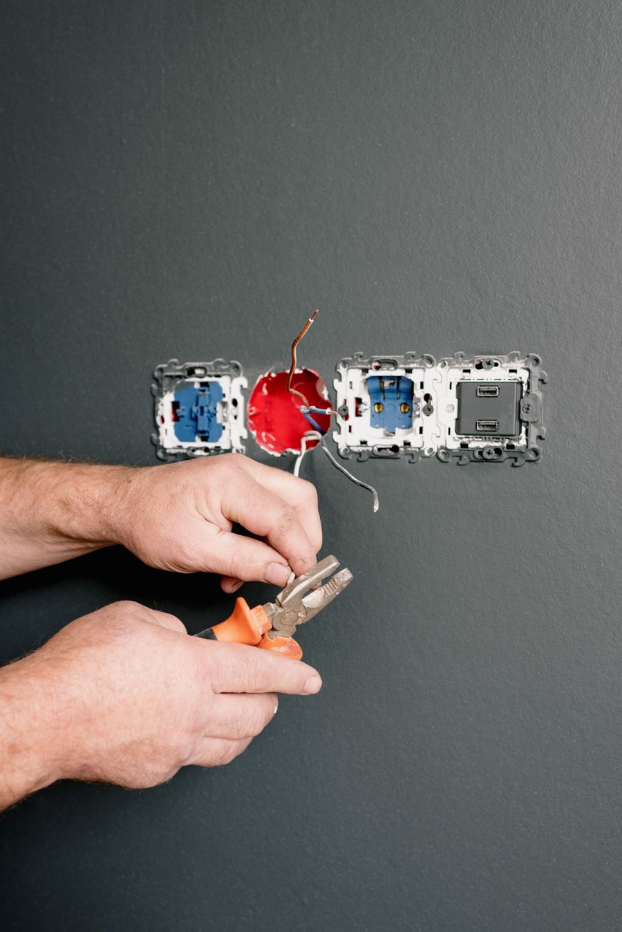 Hands using pliers to work on electrical outlets