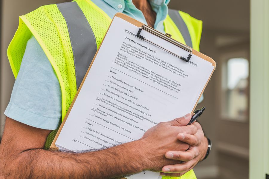 Property inspector holding an inspection checklist and pen, shown from the shoulders down