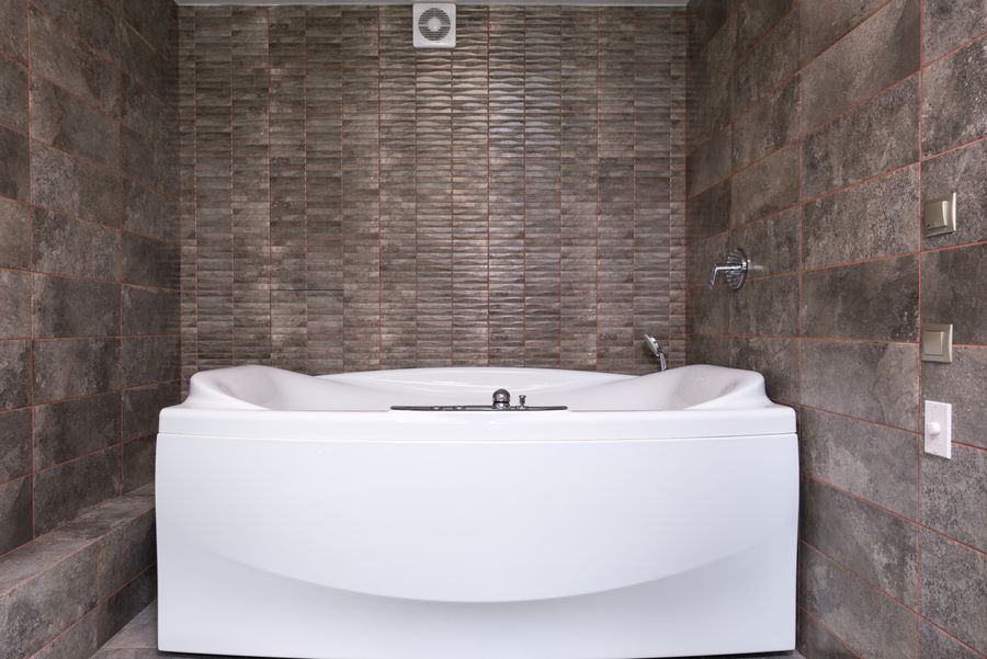 White bathtub and chrome taps surrounded by fitted wall tiles