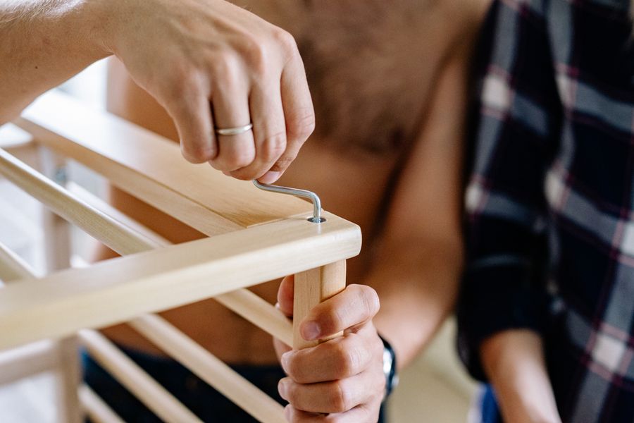 Hands tightening a wooden furniture joint with an Allen key