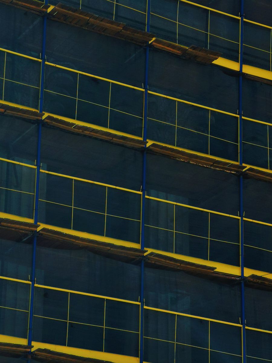 Scaffolding platforms and yellow guardrails on a building facade