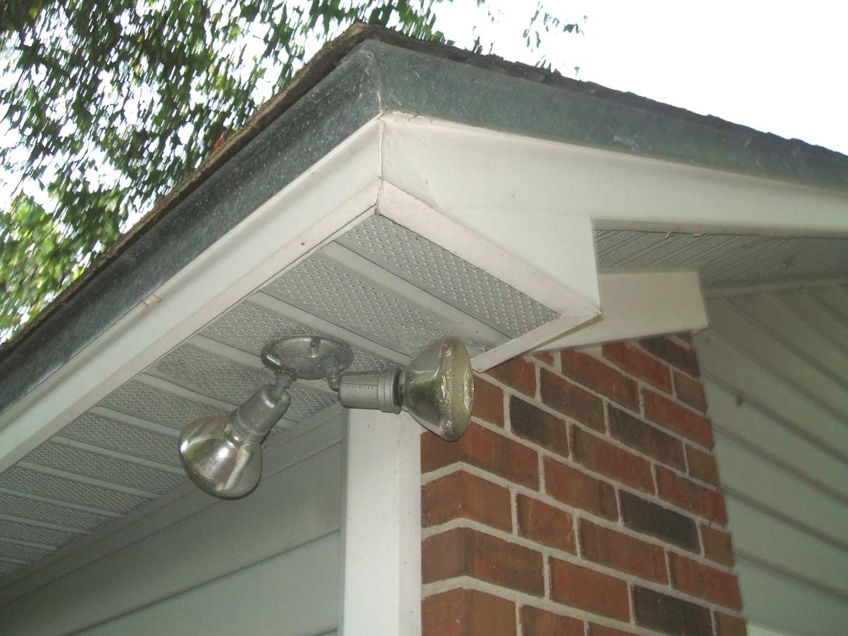 Close-up of a house roof edge with white fascia and ventilated soffit panels