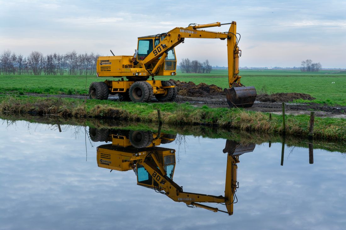Excavator preparing ground beside a field