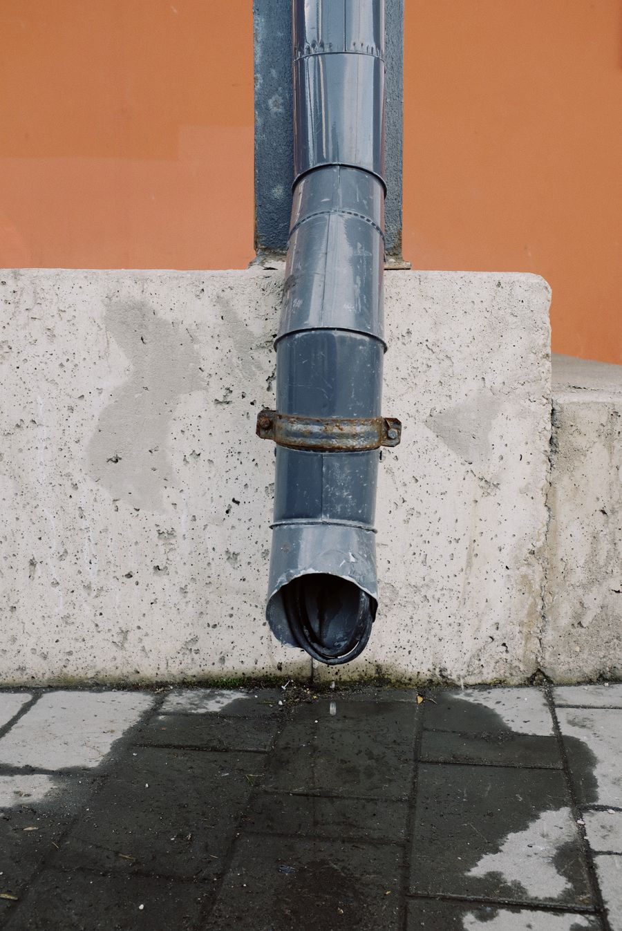 Exterior drainage downpipe with water dripping from its outlet