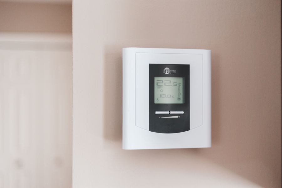 Wall-mounted digital heating thermostat displaying the room temperature